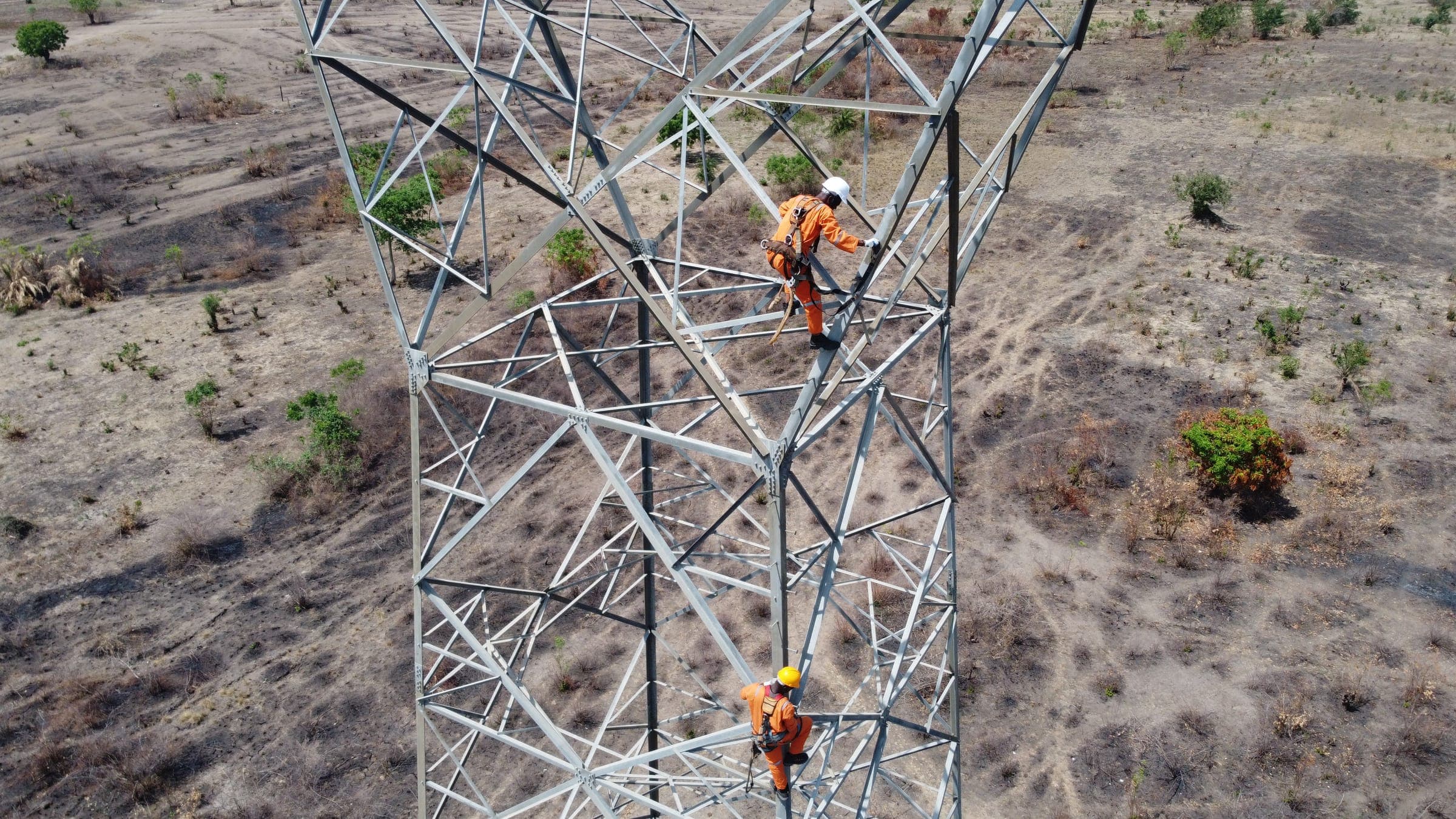 Transmission tower under construction with a worker climbing the structure